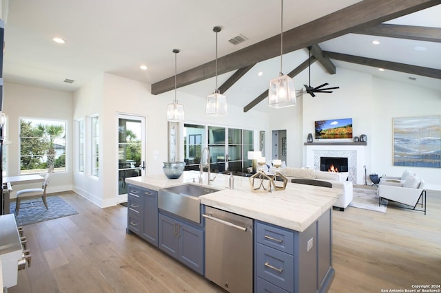 kitchen featuring sink, decorative light fixtures, a center island with sink, dishwasher, and beam ceiling