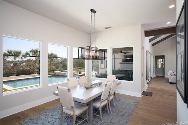 dining space featuring hardwood / wood-style floors, lofted ceiling with beams, and a chandelier