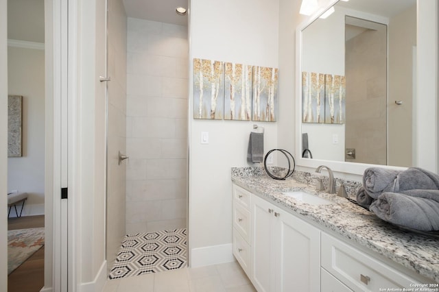 bathroom with crown molding, tile patterned floors, vanity, and a tile shower