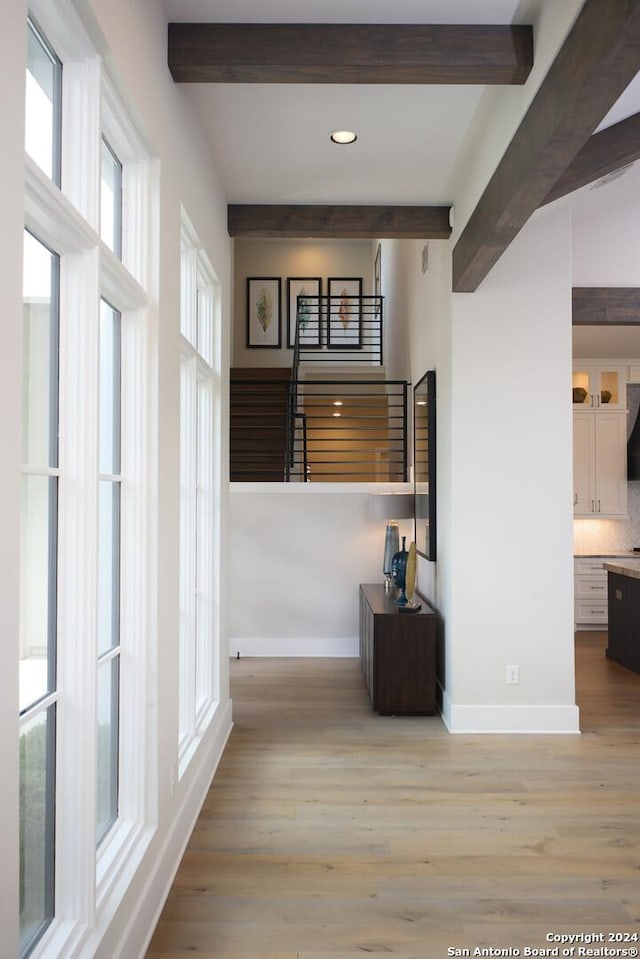 hall featuring beam ceiling and light hardwood / wood-style floors