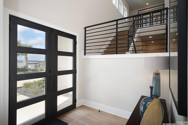 foyer with a high ceiling, wood-type flooring, a wealth of natural light, and french doors