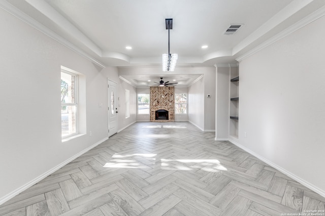 unfurnished living room featuring light parquet flooring, a fireplace, ceiling fan, and crown molding