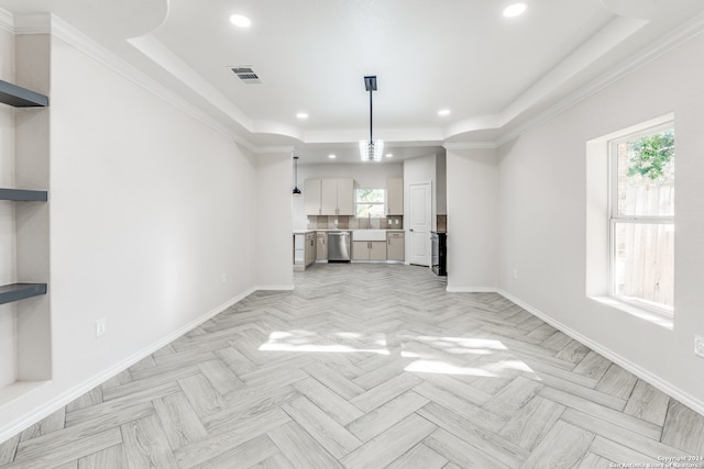 unfurnished living room with light parquet floors, a tray ceiling, and ornamental molding