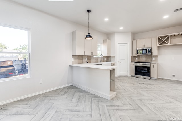 kitchen featuring white cabinetry, appliances with stainless steel finishes, backsplash, hanging light fixtures, and kitchen peninsula