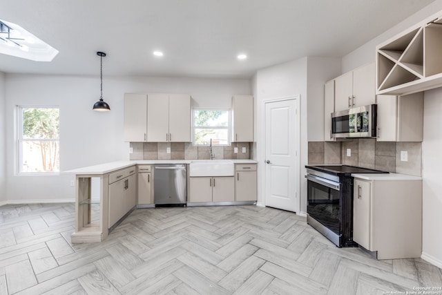 kitchen featuring stainless steel appliances, white cabinetry, backsplash, decorative light fixtures, and a skylight