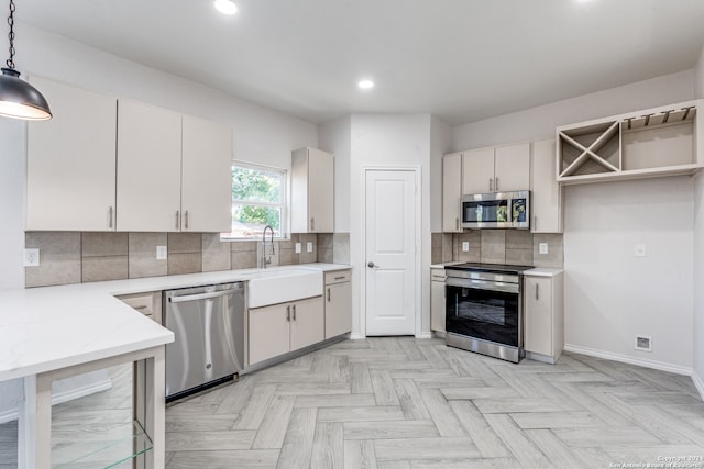 kitchen featuring light parquet flooring, white cabinetry, appliances with stainless steel finishes, hanging light fixtures, and sink