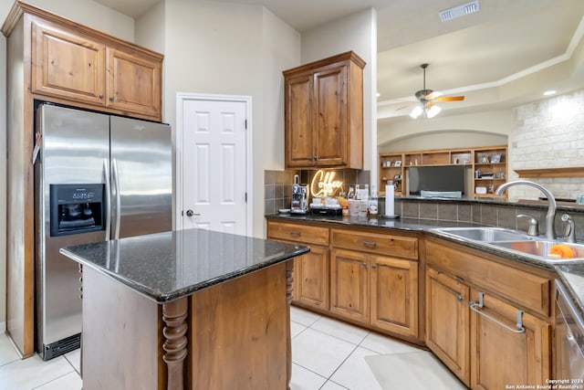 kitchen with decorative backsplash, light tile patterned floors, stainless steel appliances, sink, and a center island