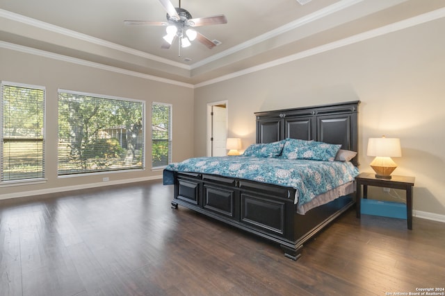 bedroom with ornamental molding, dark wood-type flooring, a raised ceiling, and ceiling fan