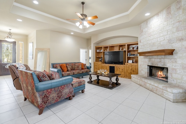 living room with light tile patterned flooring, a tray ceiling, and a fireplace