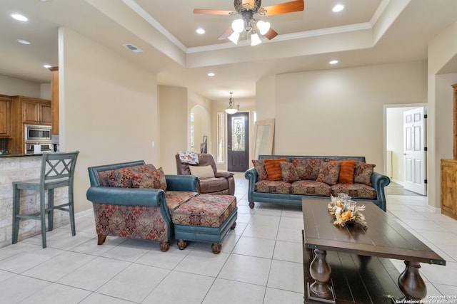 tiled living room with crown molding, a tray ceiling, and ceiling fan