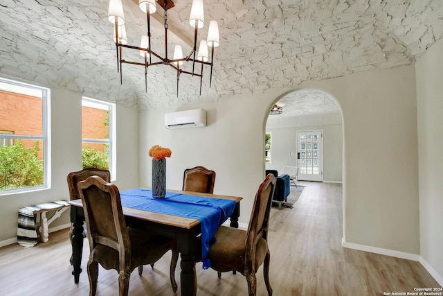 dining space featuring a notable chandelier, a wall mounted air conditioner, light wood-style flooring, baseboards, and arched walkways