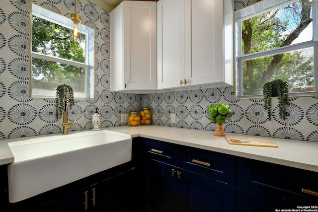 kitchen featuring backsplash, light countertops, white cabinets, and a sink