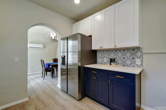 kitchen with light hardwood / wood-style flooring, a wall mounted air conditioner, white cabinetry, blue cabinetry, and stainless steel fridge with ice dispenser