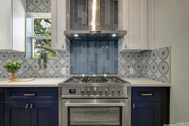 kitchen with white cabinetry, high end stove, wall chimney range hood, and backsplash