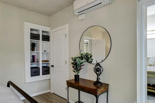 interior space with baseboards, a wall unit AC, and wood finished floors