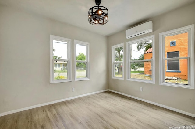 spare room with a wall mounted AC and light hardwood / wood-style floors