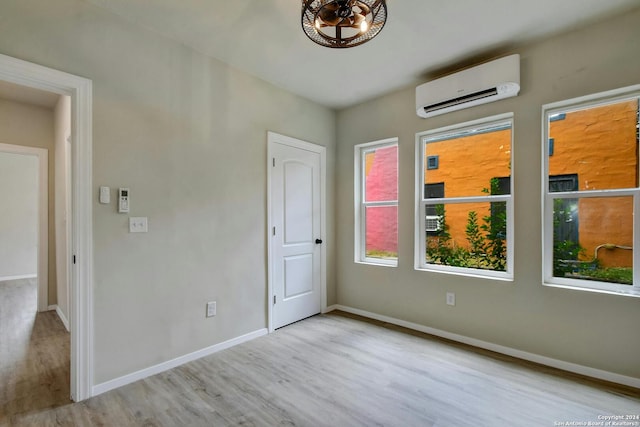 spare room with wood finished floors, baseboards, and a wall unit AC