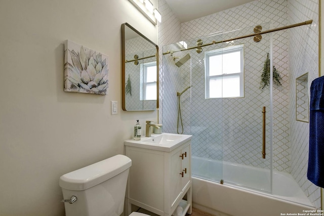 bathroom with toilet, a healthy amount of sunlight, vanity, and shower / bath combination with glass door