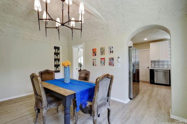 dining room featuring an inviting chandelier, built in shelves, a textured ceiling, and light hardwood / wood-style floors