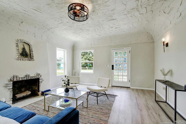 living room featuring baseboards, light wood-style floors, and a fireplace with flush hearth