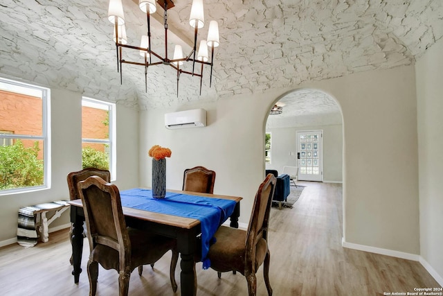 dining space with light hardwood / wood-style floors, a wall unit AC, and an inviting chandelier