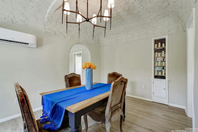 dining room featuring an inviting chandelier, an AC wall unit, baseboards, and wood finished floors