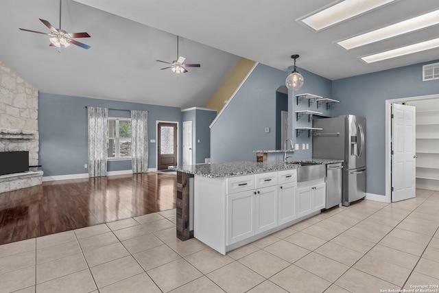 kitchen with sink, light hardwood / wood-style floors, pendant lighting, white cabinets, and light stone counters