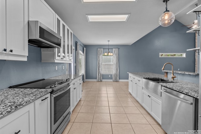 kitchen with appliances with stainless steel finishes, white cabinetry, light stone countertops, and light tile patterned flooring