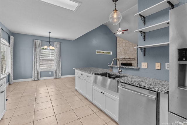 kitchen with appliances with stainless steel finishes, white cabinetry, lofted ceiling, light stone counters, and light tile patterned floors