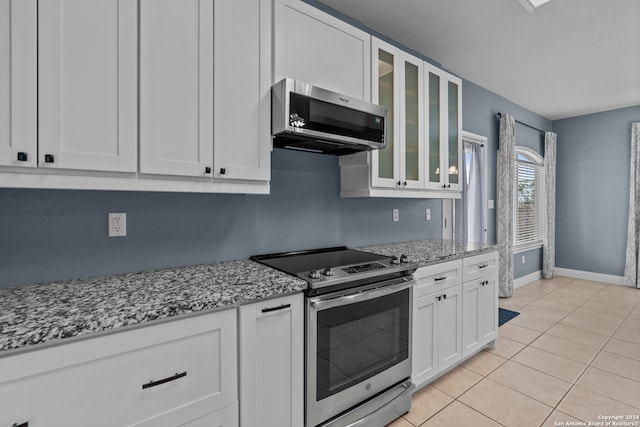 kitchen featuring light stone counters, stainless steel appliances, light tile patterned flooring, and white cabinets