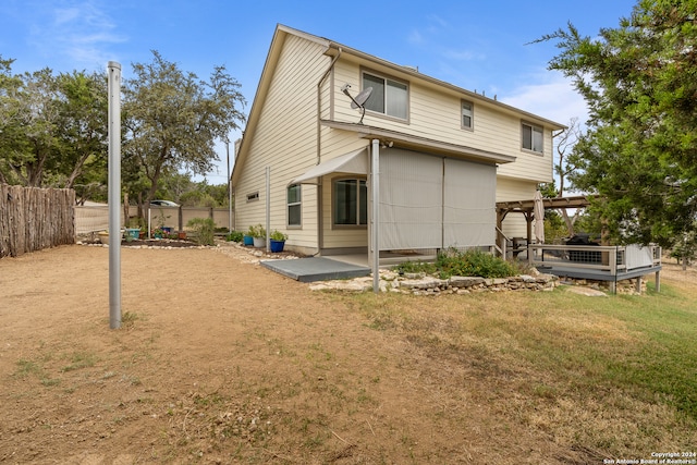 rear view of property with a yard, a deck, and a patio area