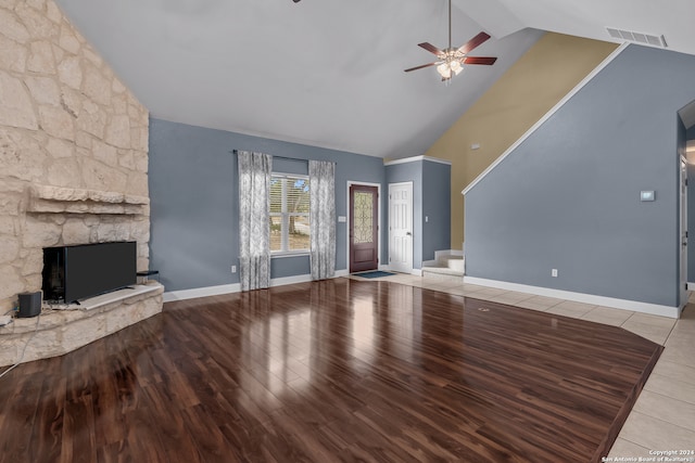 unfurnished living room featuring a stone fireplace, hardwood / wood-style floors, ceiling fan, beamed ceiling, and high vaulted ceiling