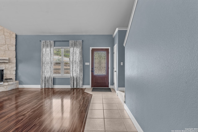 entryway featuring ornamental molding, a fireplace, and light wood-type flooring