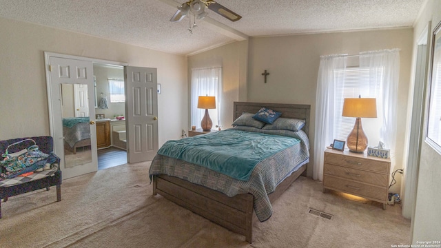 carpeted bedroom with ensuite bath, lofted ceiling, a textured ceiling, and ceiling fan