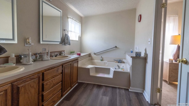 bathroom with vanity, hardwood / wood-style floors, a bathtub, and a textured ceiling