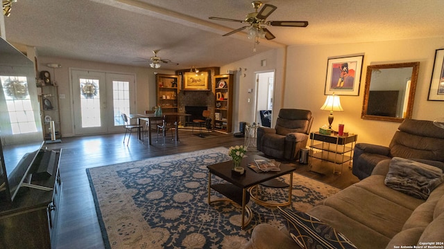 living room featuring dark wood-type flooring, vaulted ceiling, a textured ceiling, and ceiling fan