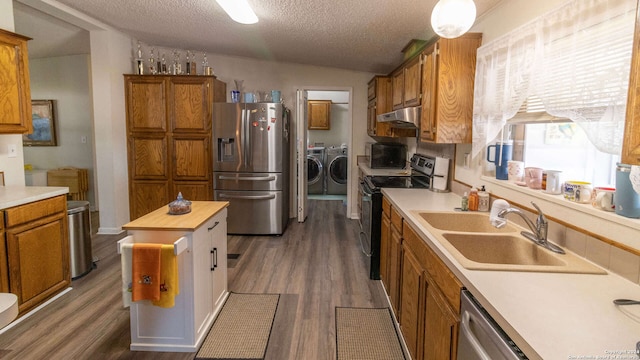 kitchen with lofted ceiling, appliances with stainless steel finishes, a textured ceiling, washing machine and dryer, and wooden counters