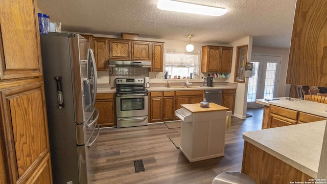 kitchen featuring stainless steel appliances, sink, a center island, a textured ceiling, and dark hardwood / wood-style flooring