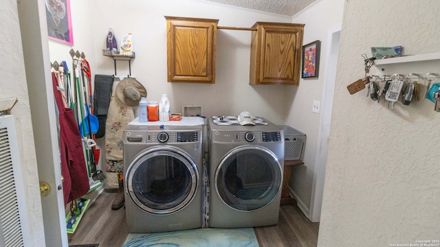 laundry area featuring cabinets, hardwood / wood-style floors, a textured ceiling, and washer and clothes dryer