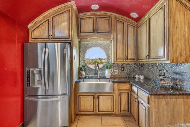 kitchen with tasteful backsplash, light tile patterned floors, stainless steel fridge with ice dispenser, vaulted ceiling, and sink