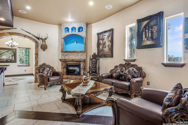 living room featuring a stone fireplace and an inviting chandelier