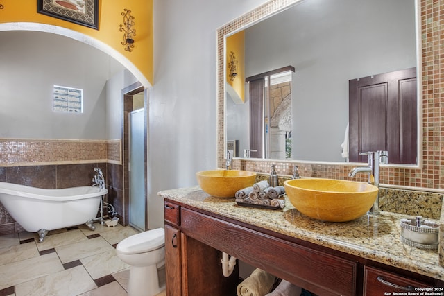 bathroom featuring tile walls, vanity, toilet, and a wealth of natural light