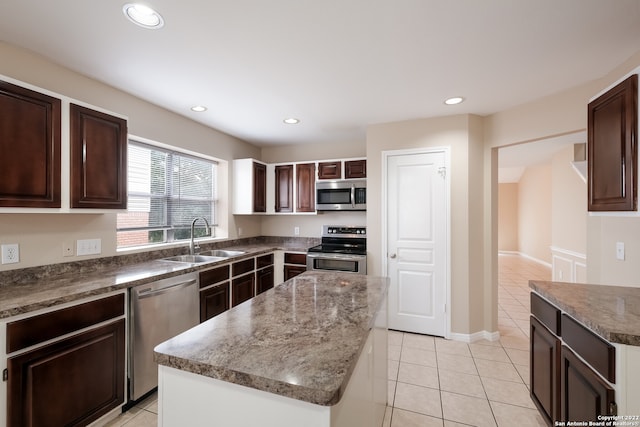 kitchen with sink, a kitchen island, stainless steel appliances, dark brown cabinetry, and light tile patterned floors