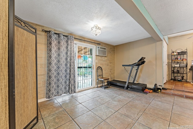 workout room with a wall mounted AC, tile patterned floors, and a textured ceiling