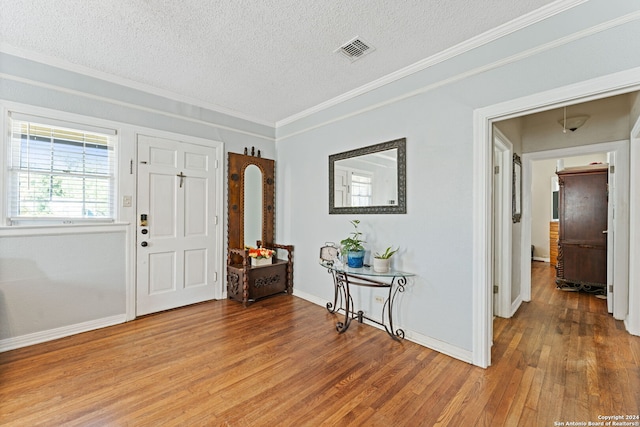 entryway featuring a textured ceiling, ornamental molding, and hardwood / wood-style floors