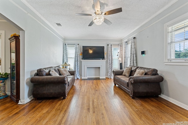 living room featuring a wealth of natural light, crown molding, and light hardwood / wood-style floors