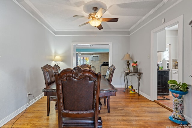 dining space with a wall unit AC, light hardwood / wood-style flooring, ornamental molding, a textured ceiling, and ceiling fan