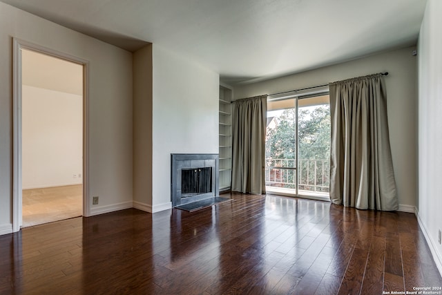 unfurnished living room featuring built in shelves and dark hardwood / wood-style floors