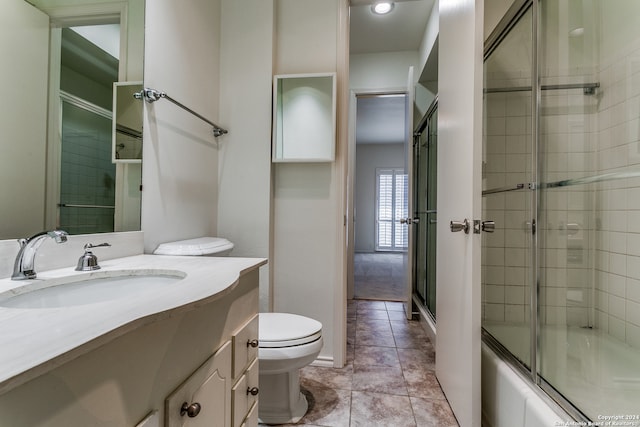 full bathroom featuring vanity, toilet, tile patterned floors, and bath / shower combo with glass door