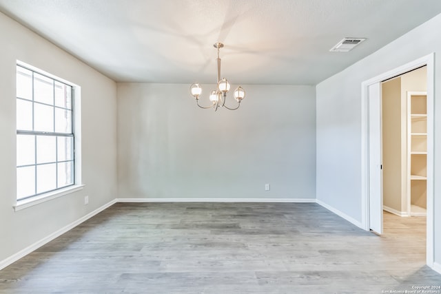 empty room featuring an inviting chandelier and hardwood / wood-style flooring